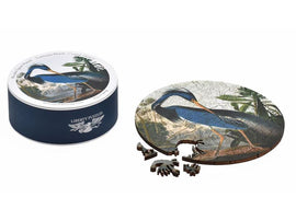 The Louisiana Heron jigsaw puzzle by Liberty Puzzles is showcased in a round container, with a detailed image of a heron in a lush setting. The circular puzzle pieces are displayed next to the solved portion, illustrating the vibrant colors and intricate design of the heron.
