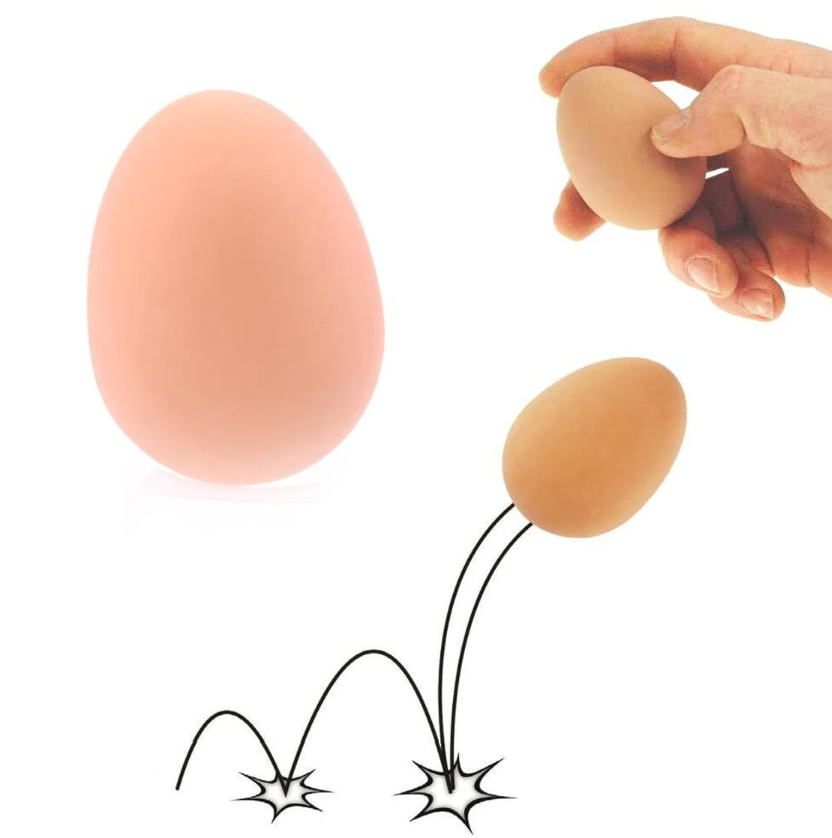 A playful Egg Bouncy Ball from One for Fun. The image showcases two egg-shaped balls, one larger and one smaller, with motion lines indicating bouncing action. The larger ball is a soft, peach-colored egg, while the smaller one is being held in a hand, demonstrating its bouncy quality. Ideal for fun and stress relief.