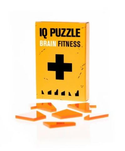 The IQ Puzzle Greek Cross by GEEK Toys US, featuring a bright yellow box with a black plus sign, showcasing various brightly colored puzzle pieces scattered around it. The packaging highlights 'Brain Fitness' for enhancing cognitive skills.