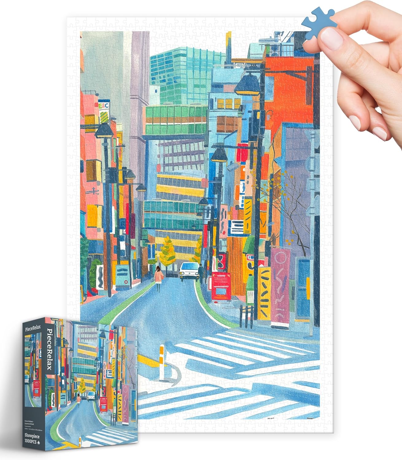 A colorful jigsaw puzzle featuring a vibrant Japanese street scene. The puzzle is partially completed, showcasing various buildings, traffic lights, and pedestrians. A hand is holding a blue puzzle piece ready to be placed. The puzzle box for the Pintoo Corporation's creation, titled 'Grace Helmer - Japanese Street', is positioned in the foreground.