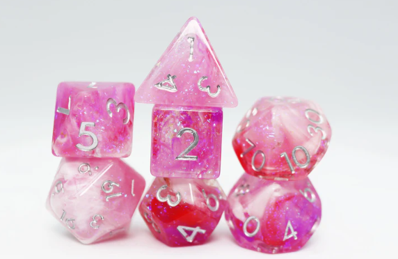 A set of Flushed Frost RPG dice by Foam Brain Games, featuring vibrant pink colors with glittery swirls. The set includes various geometric shapes with clear numbering, ideal for tabletop gaming. Each die showcases a unique blend of translucent pink and red hues, creating an eye-catching display perfect for enhancing any RPG experience.