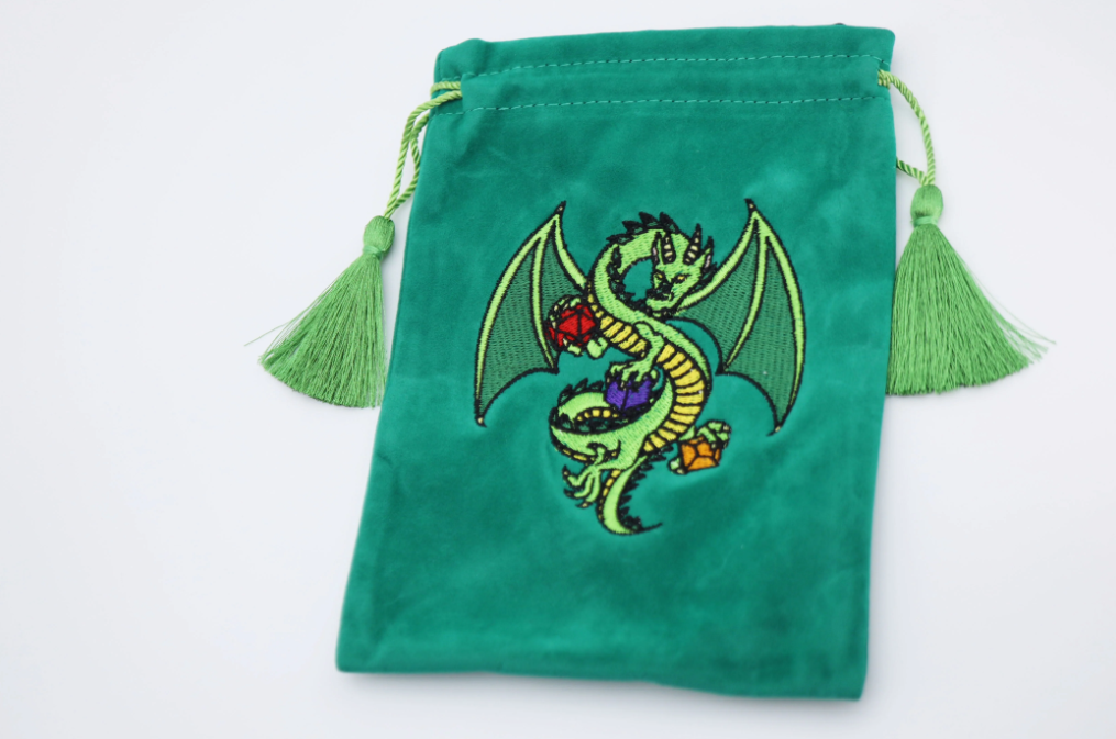 A vibrant green dice bag featuring an intricately embroidered dragon design. The dragon is depicted in shades of green, adorned with colorful gemstones. The bag is made from soft fabric and includes decorative tassels on the drawstring. This stylish accessory is perfect for storing dice and other gaming essentials, showcasing a fantasy theme that appeals to tabletop gamers.