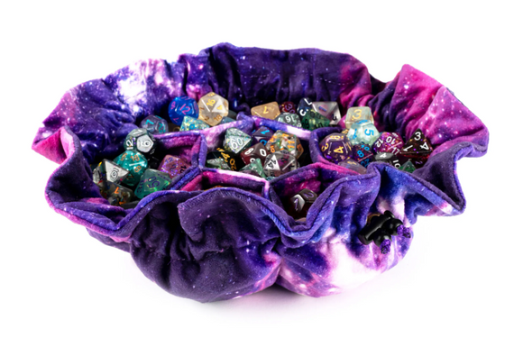 A vibrant Nebula Velvet 7 Pocket Dice Bag by FanRoll, featuring a galaxy-inspired design in purple and blue, filled with a variety of colorful polyhedral dice. The bag has a unique petal-like shape with seven sections to organize and store dice securely, making it perfect for tabletop gaming enthusiasts.