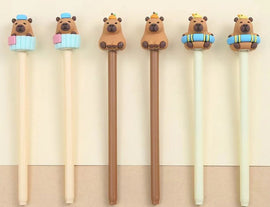 A set of cute gel pens designed by BC Mini featuring capybara toppers. The pens come in various colors with adorable capybaras sitting on decorative elements like cupcakes and lifebuoys.