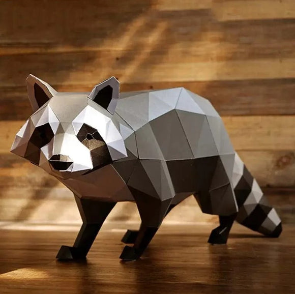 A beautifully crafted 3D papercraft raccoon model from Papercraft World. The geometric design features a blend of gray, black, and white shades, highlighting its intricate details. The raccoon stands in a dynamic pose on a wooden surface, showcasing the artistic flair of DIY papercrafting.