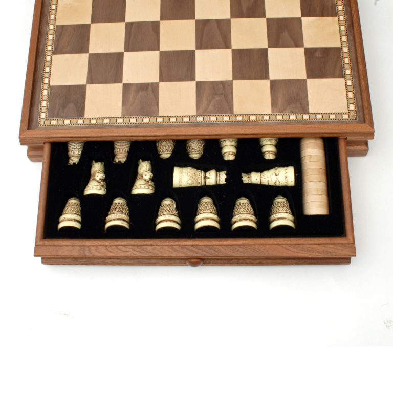 A beautifully crafted medieval-themed chess set featuring intricately designed pieces. The wooden chessboard is elegantly inlaid, and the pieces are stored in a plush black-lined drawer. The set includes classic chess figures such as knights, rooks, and kings, each with detailed carvings that reflect a medieval aesthetic.