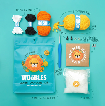 Sebastian the Lion Beginner Crochet Kit from The Woobles. The kit includes a colorful assortment of yarn, a crochet hook, eyes, stuffing, and step-by-step video instructions, all neatly packaged in a vibrant bag. Perfect for beginners wanting to learn to crochet.
