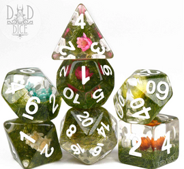 A vibrant set of seven RPG dice featuring a Prairie Flowers design. Each die is encased in transparent resin filled with miniature flowers and greenery, displaying clear white numbers for easy readability. The set includes a variety of shapes such as a D20, D12, D10, D8, D6, and D4, perfect for tabletop gaming enthusiasts.