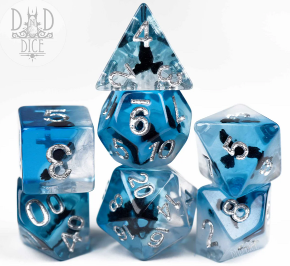 Dark Wings 7-piece RPG dice set featuring dice in various shapes and sizes. Each die is made of translucent blue material with silver metallic numbers and intricate dark wing designs. The set includes a twenty-sided die, a ten-sided die, and more, perfect for tabletop gaming enthusiasts.