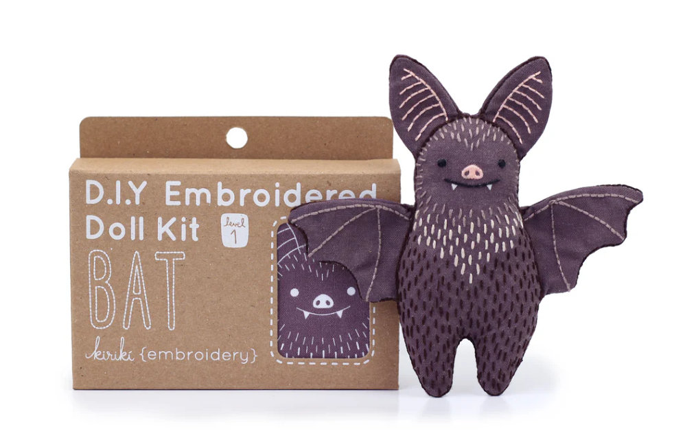 The Bat Doll Embroidery Kit by Kiriki Press is a DIY craft kit featuring a cute bat doll with embroidered details. The kit comes in a cardboard box labeled 'D.I.Y Embroidered Doll Kit' and includes everything needed to create this adorable plush bat, perfect for crafters and enthusiasts alike.