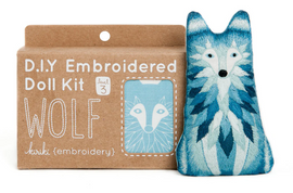 The Wolf Doll Embroidery Kit by Kiriki Press features an intricate embroidered doll in shades of blue and white, displaying a wolf design. The kit is presented in eco-friendly packaging with the title 'D.I.Y Embroidered Doll Kit' prominently displayed. It also indicates a difficulty level of 3, suitable for intermediate crafters, along with a graphic of the finished wolf doll. Perfect for DIY enthusiasts looking to create a unique decorative piece.