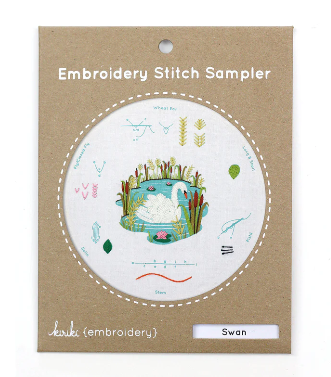 Swan Embroidery Stitch Sampler by Kiriki Press, designed as a DIY kit. The sampler features a lovely embroidered swan in a decorative tub surrounded by various stitches demonstrated like Wheat Ear and Stem. Ideal for embroidery enthusiasts and beginners to practice and learn different stitching techniques.