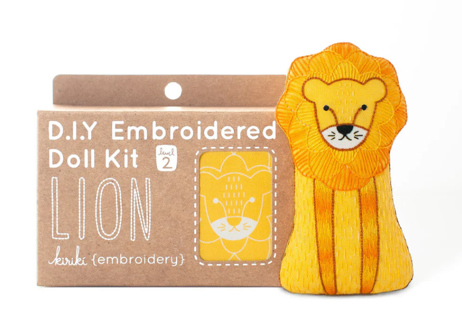 Kiriki Press Lion Doll Embroidery Kit, featuring an adorable embroidered lion design in vibrant yellow and orange colors. The kit includes materials for creating a plush lion doll, labeled as level 2 for intermediate skill levels.