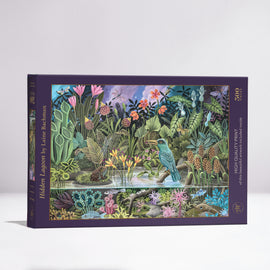 A vibrant jigsaw puzzle titled 'Hidden Lagoon' by Laine Bachman, featuring a lush scene with diverse plants and wildlife, including a bird, frogs, and colorful flowers. The puzzle comes in a beautifully illustrated box displaying 500 pieces and highlights the high-quality print of the artwork.