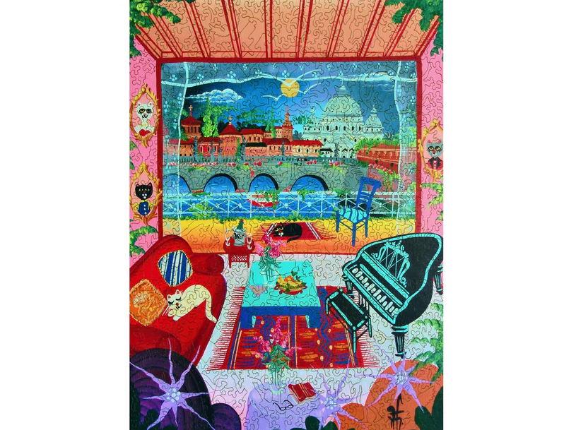 A vibrant jigsaw puzzle depicting an artistic view of Rome, Italy. The scene features a cozy room with a red couch, a grand piano, and a beautiful balcony view of Roman architecture, mountains, and a sunny sky. Cat and floral decor add charm to the interior.