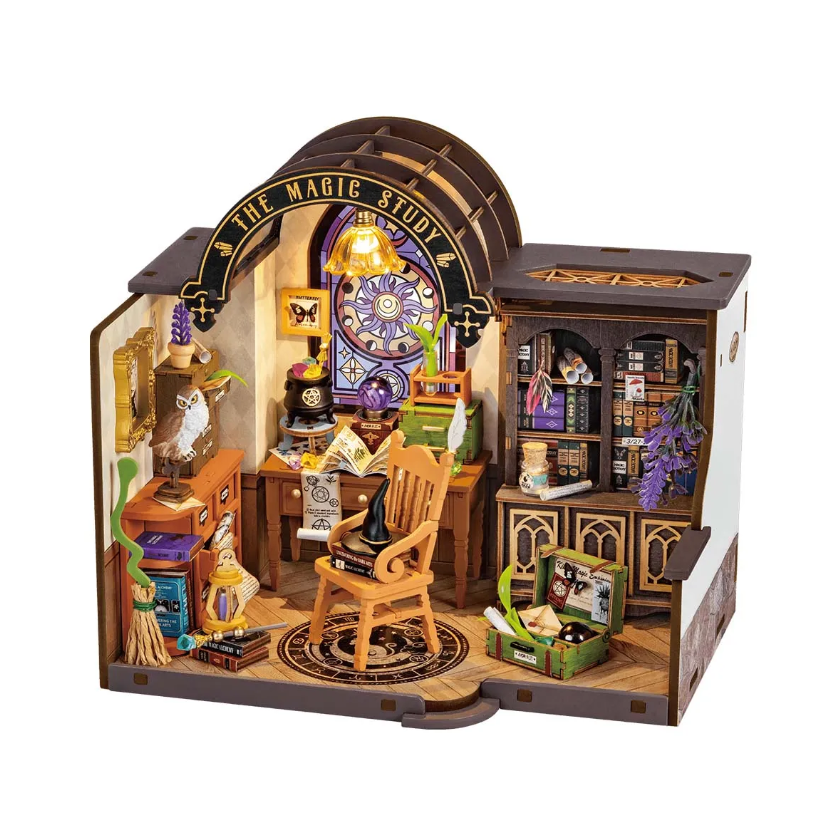 A detailed DIY model kit titled 'The Magic Study' by Robotime, featuring an intricately designed wizard's study. The scene includes a wooden chair, a desk cluttered with magical books and objects, and decorative elements such as an owl figurine, a globe, potions, and a charming stained glass window. The warm lighting adds a cozy atmosphere to this enchanting workspace.