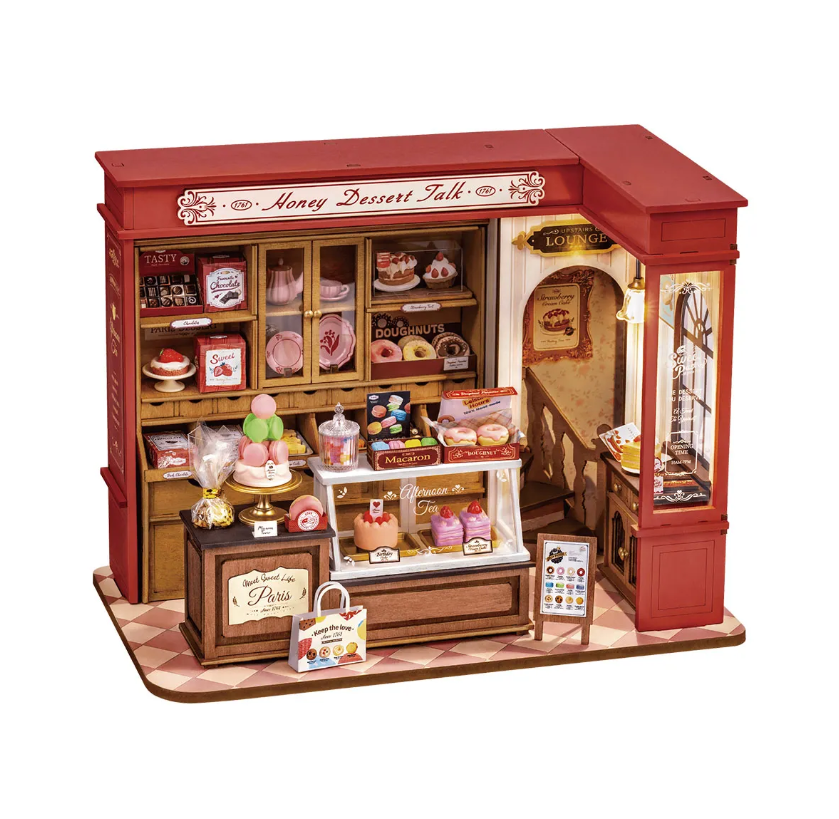 The Honey Dessert Talk model by Robotime is a beautifully detailed DIY kit showcasing a charming dessert shop. It features shelves filled with a variety of sweet treats like cakes, doughnuts, and macarons, alongside vibrant display cases, elegant signage, and a cozy lounge area, all crafted to create a whimsical and inviting atmosphere.