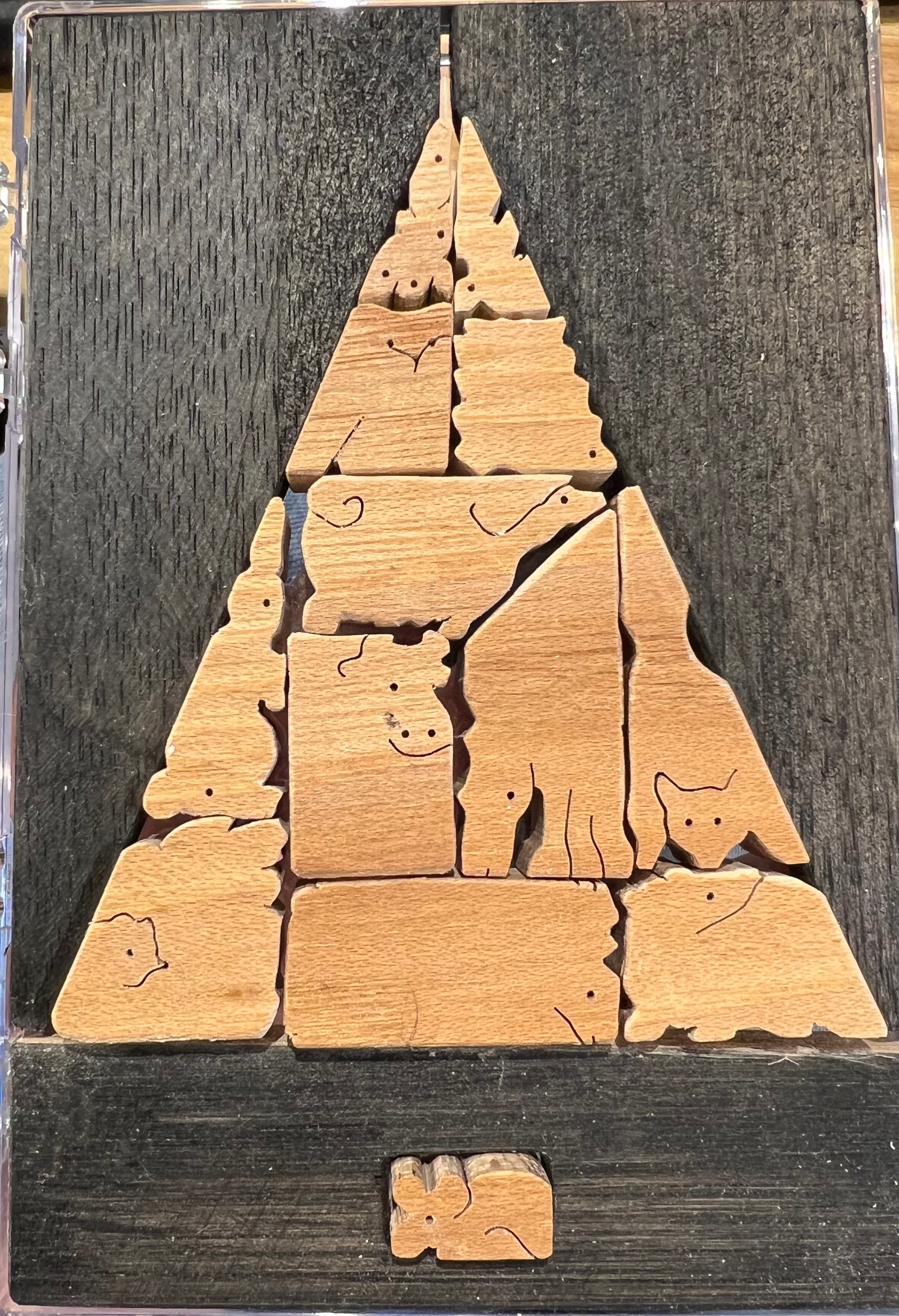 A creative wooden jigsaw puzzle arranged in the shape of a Christmas tree. The puzzle pieces feature charming animal designs, including a rabbit, cat, and cow, all displayed on a dark wooden background. Perfect for family fun and enhancing problem-solving skills.