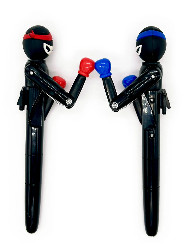 The Ninja Knockout Action Pen by Snifty features two playful ninja figures in vibrant colors. One ninja wears a red headband and boxing gloves, while the other wears a blue headband and boxing gloves. Both are posed as if preparing for a friendly match, showcasing a unique and whimsical design. Designed for fun or practical use, this pen makes a great gift or desk accessory.