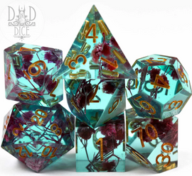 A vibrant 7-piece set of acrylic RPG dice designed for tabletop gaming, featuring a translucent aqua color embedded with dried flowers, and gold numbering. The set includes various polyhedral shapes, ideal for enhancing gameplay experiences in RPGs like Dungeons & Dragons.