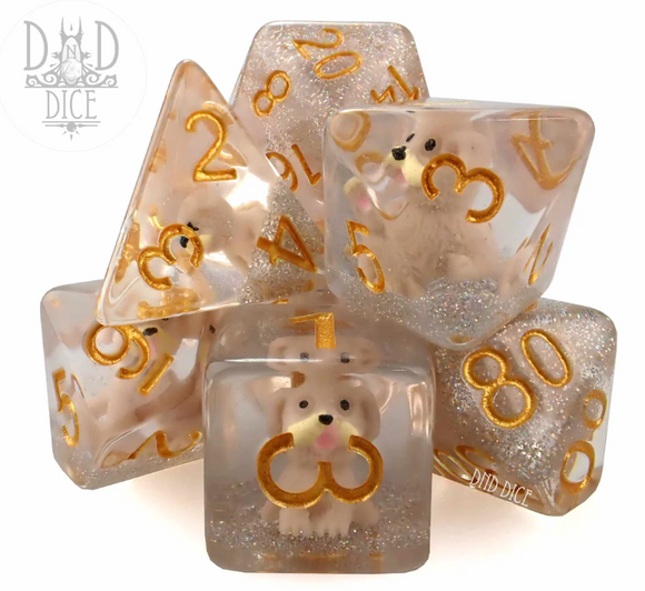 A colorful 7-piece RPG dice set made by DND Dice. The set features transparent dice with gold numbers and embedded cute dog figures. The dice vary in shape, including d4, d6, d8, d10, d12, and d20, showcasing a sparkling glitter effect.