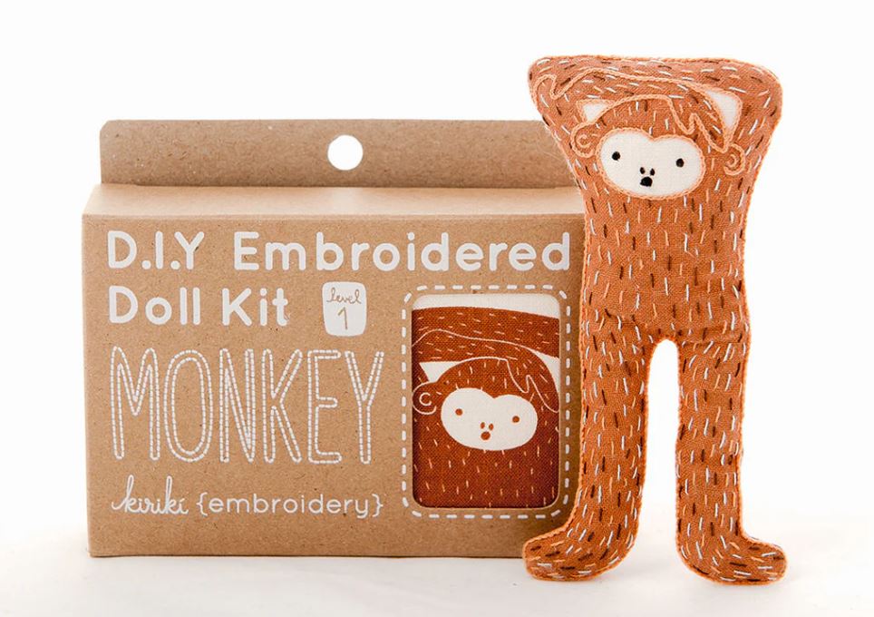 Monkey Doll Embroidery Kit by Kiriki Press featuring a cute, handcrafted monkey doll design. The kit comes in a level 1 difficulty, perfect for beginners who want to explore DIY embroidery. The packaging showcases the signature monkey illustration, and the doll is displayed in a lively orange color, ready to be stitched.