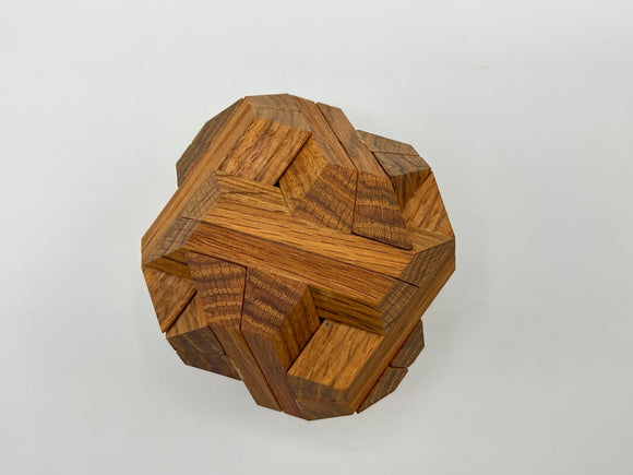 A top view of the Egyptian - STC 23A mechanical puzzle by Stewart Coffin, featuring intricately interlocking wooden pieces in a geometric shape, highlighting varied textures and rich wood tones.
