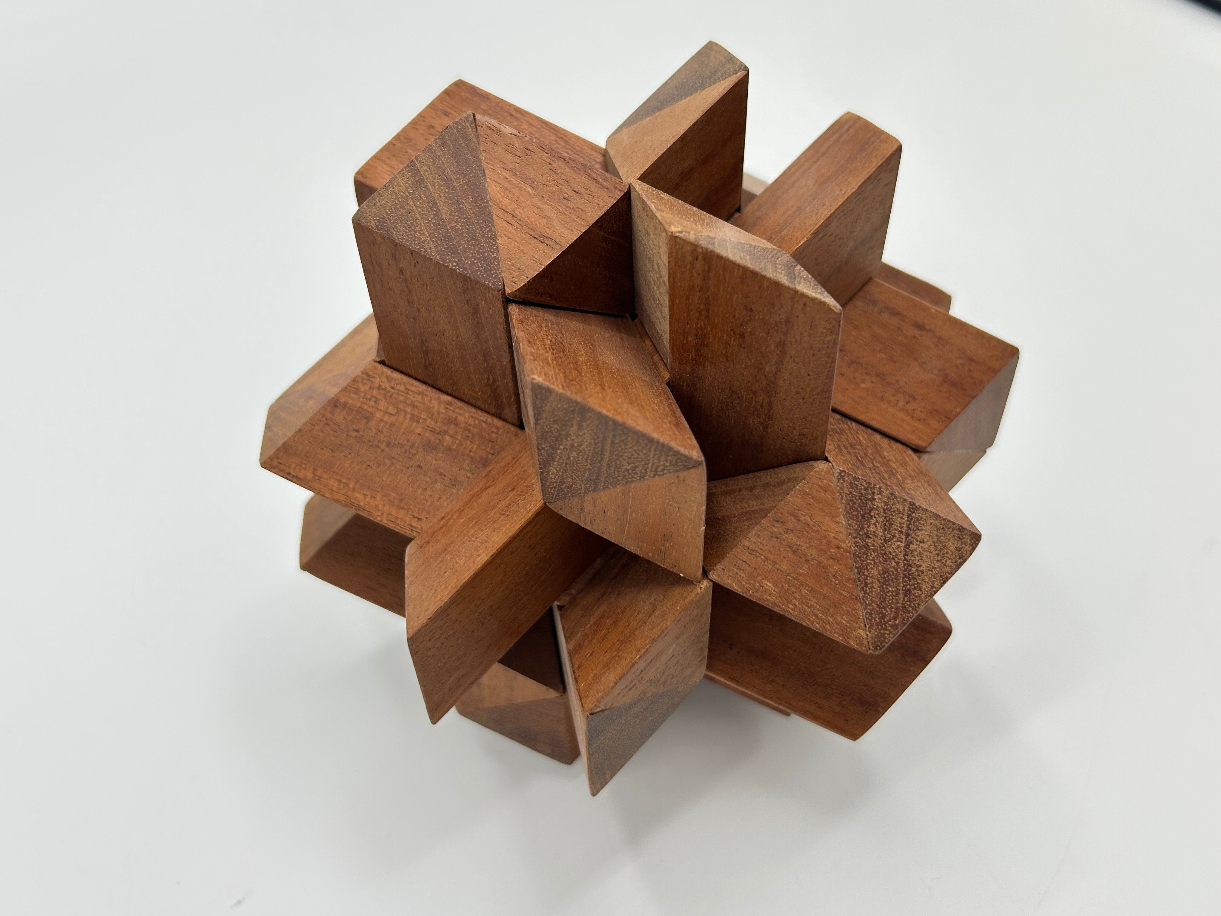 A beautifully crafted wooden mechanical puzzle composed of twelve interlocking pieces, showcasing a fascinating geometric design with a smooth finish. The pieces are arranged to form a star-like structure, highlighting intricate angles and textures that exemplify expert craftsmanship by Stewart Coffin.