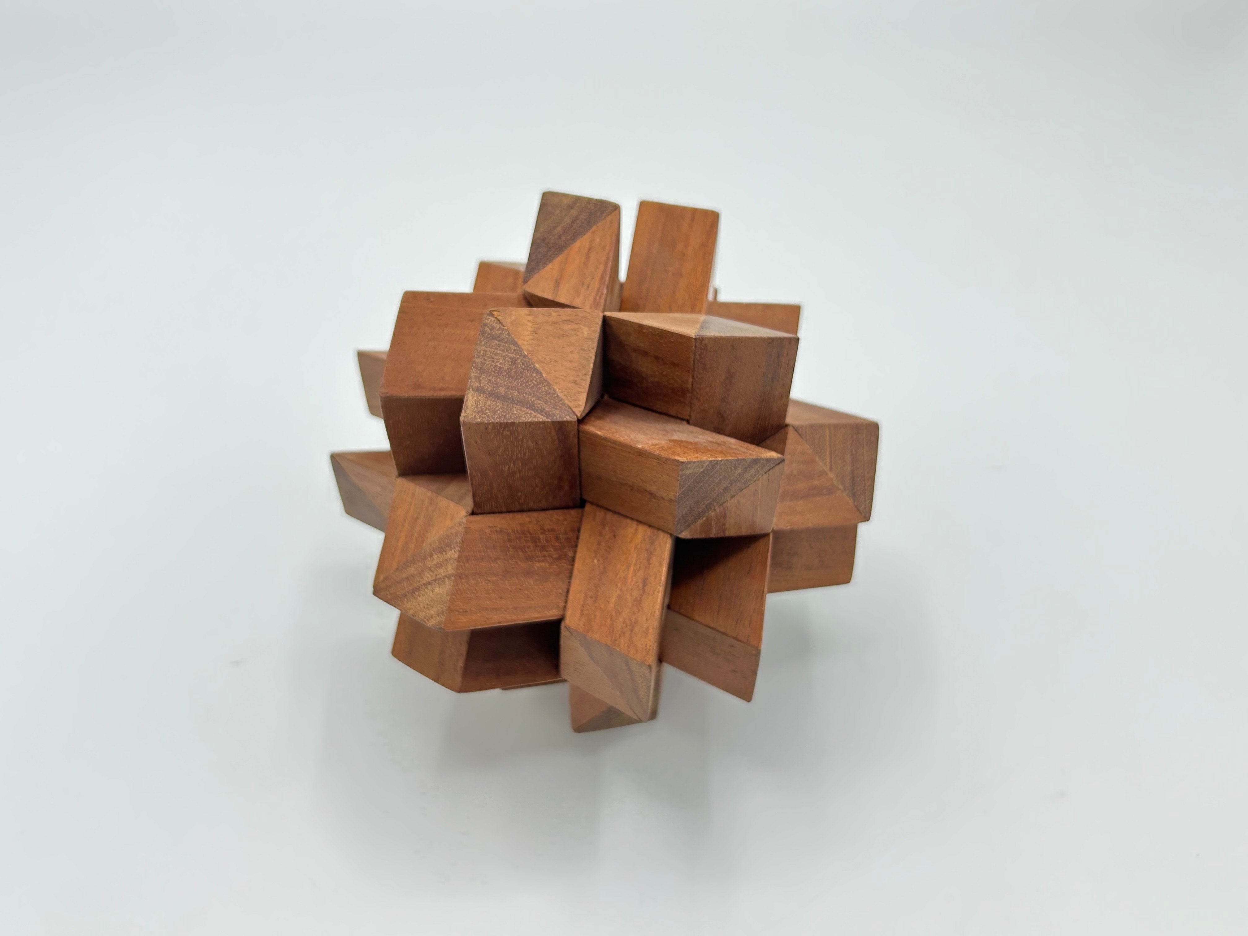Twelve Piece Separation-STC 85 by Stewart Coffin, crafted from intricately joined wooden pieces, forming a unique and engaging mechanical puzzle. The puzzle features various geometric shapes and a compact, artistic design, ideal for enhancing spatial reasoning and providing an enjoyable challenge for enthusiasts.