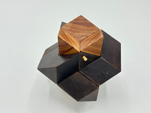 Rosebud -STC #39 with peg is a beautifully crafted mechanical puzzle by Stewart Coffin. It features an intricate design with contrasting dark and light wood pieces that fit together to form a multi-dimensional shape, providing a challenging yet rewarding experience for puzzle enthusiasts.