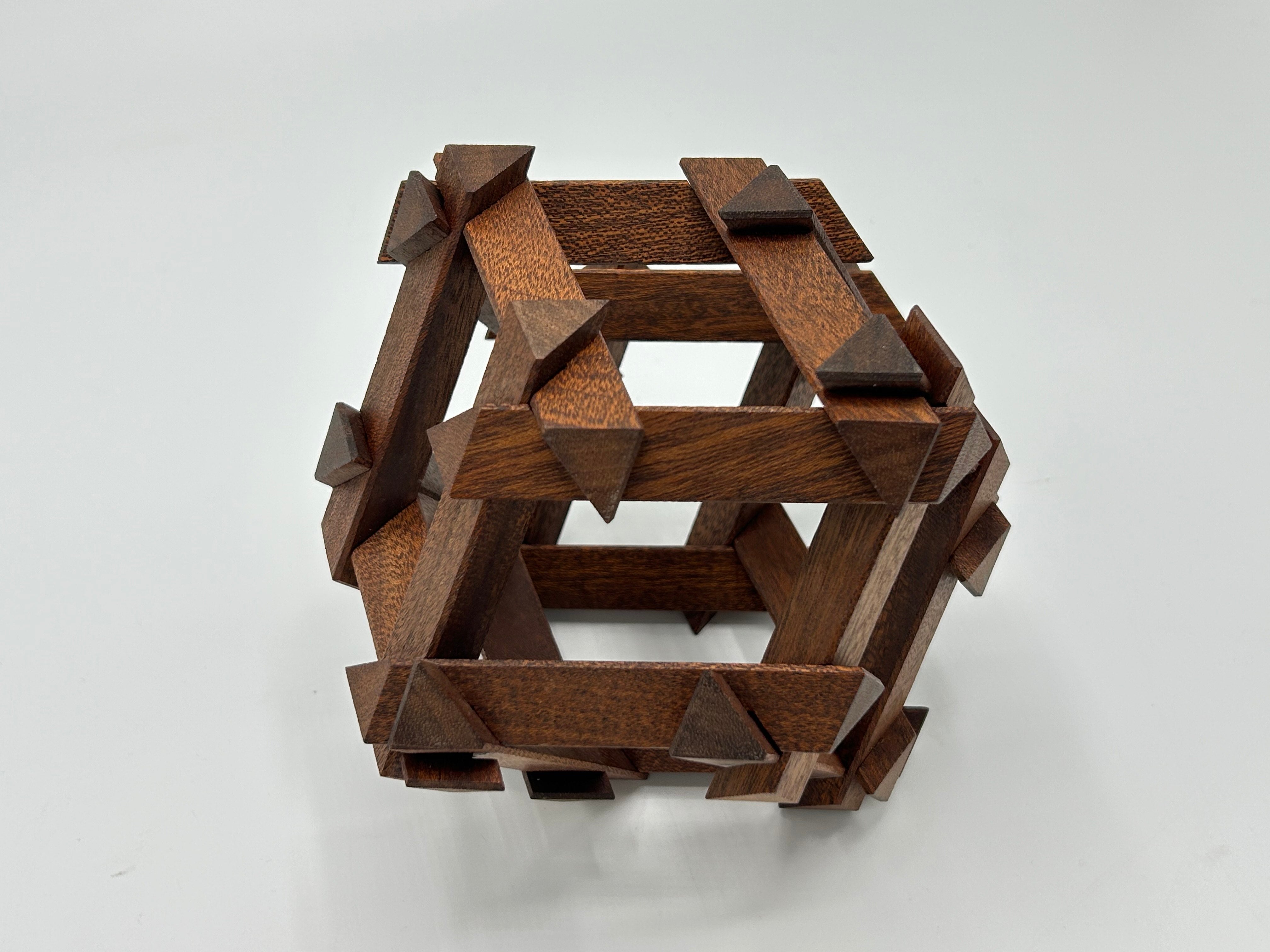 Top view of the RD Skeleton by Dubois, a handcrafted wooden mechanical puzzle featuring intricate interlocking pieces, designed by Philippe Dubois. The puzzle showcases a rich brown finish with pointed accents, enhancing its artistic appeal.