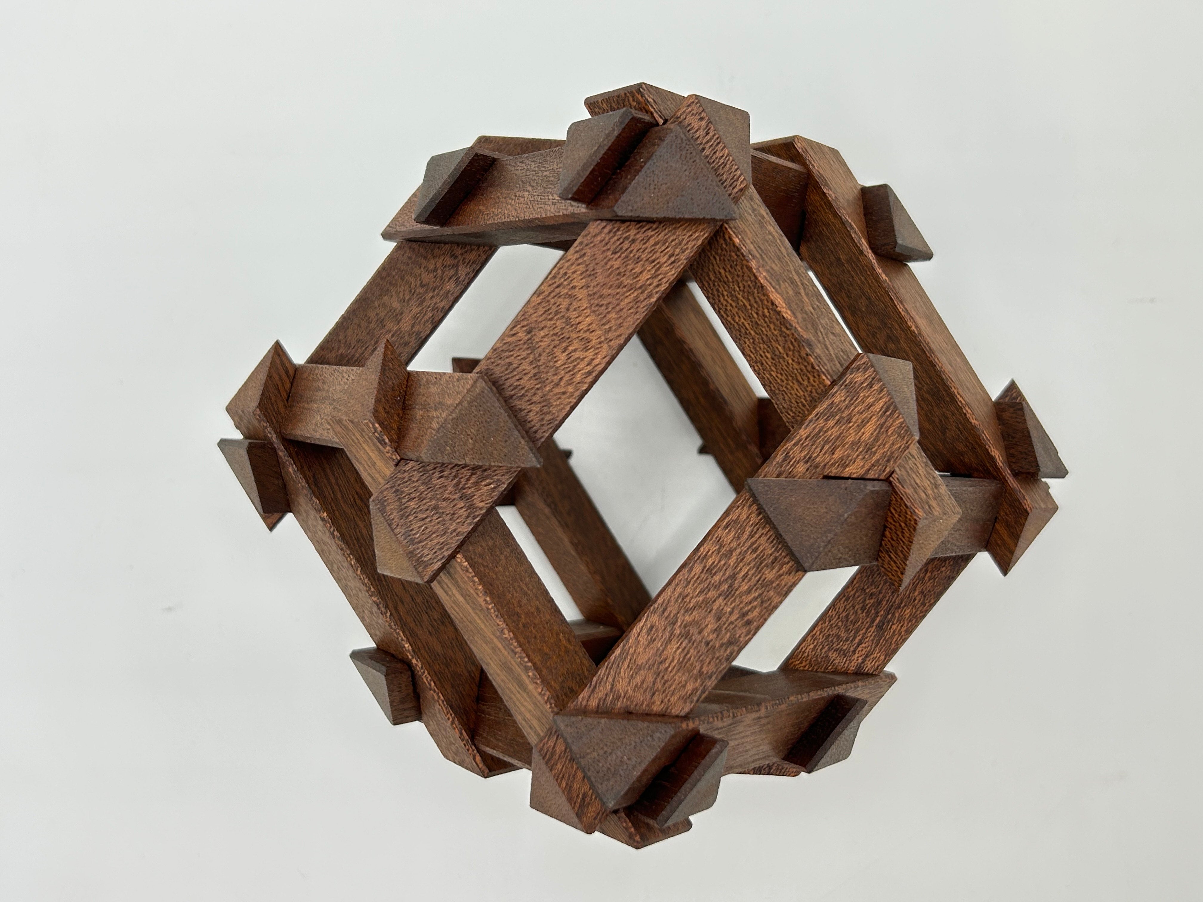The RD Skeleton by Dubois is a beautifully crafted mechanical puzzle made from rich, dark wood. Its intricate design features interlocking geometric shapes that create a visually stunning 3D structure. The puzzle emphasizes both art and mechanics, offering a challenging yet rewarding experience for puzzle enthusiasts.