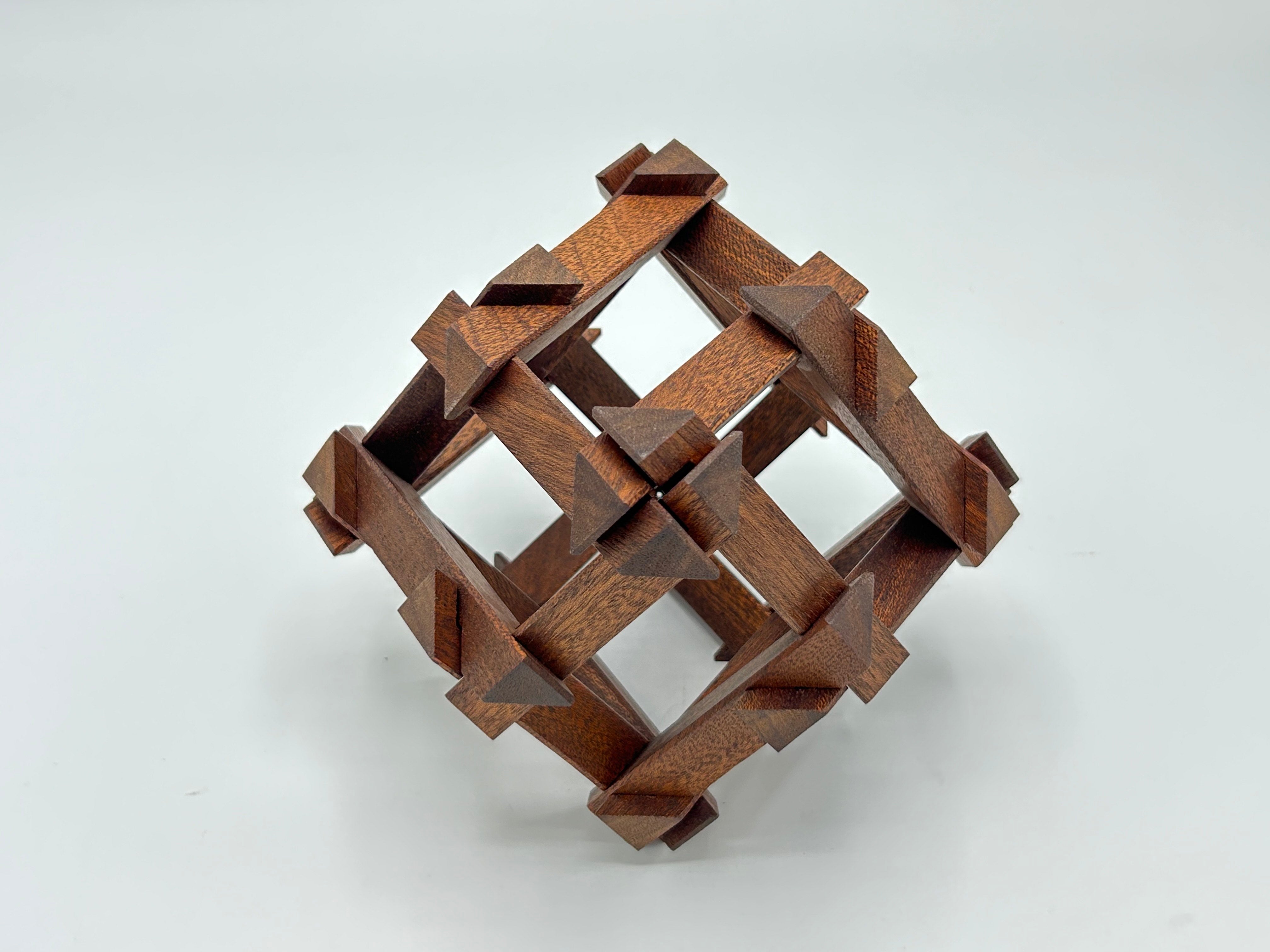 The RD Skeleton by Dubois is a beautifully crafted mechanical puzzle made of dark wood. Its intricate design features a three-dimensional woven pattern with pointed ends, creatively challenging the solver to disassemble and reassemble its pieces. This luxurious puzzle is perfect for enthusiasts seeking both beauty and brain-teasing fun.