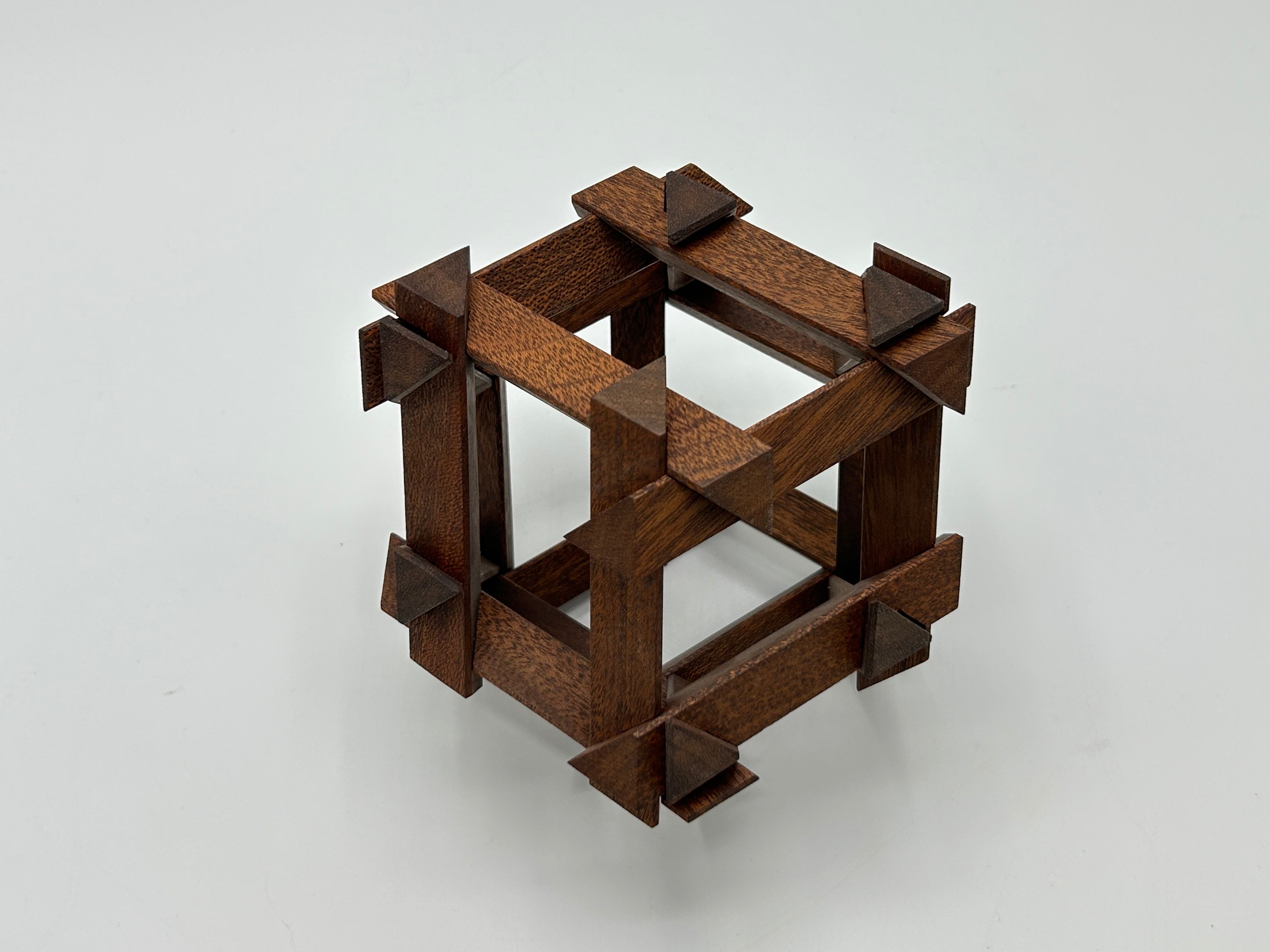 The RD Skeleton by Dubois is a beautifully crafted mechanical puzzle made from rich brown wood. Its design features a unique arrangement of wooden pieces forming a cube, with geometric shapes enhancing its structure. This intricate puzzle challenges your problem-solving skills while providing a visually appealing addition to any puzzle collection.