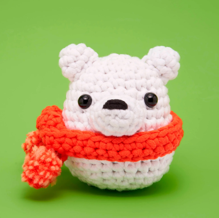 Lola Loca the Polar Bear is an adorable DIY crochet kit by Woobles. It features a cute, round bear figure with a white body and a bright orange scarf, perfect for crafters and kids alike.