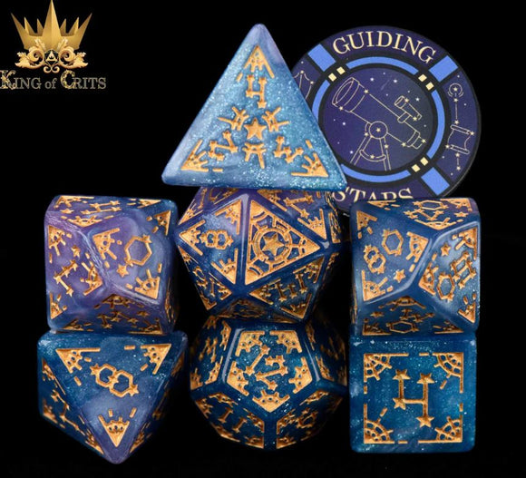 A colorful 7-piece RPG dice set featuring intricate designs in shades of blue and purple with gold accents. Includes various polyhedral dice and a 'Guiding Stars' promotional disc, perfect for tabletop gaming enthusiasts.