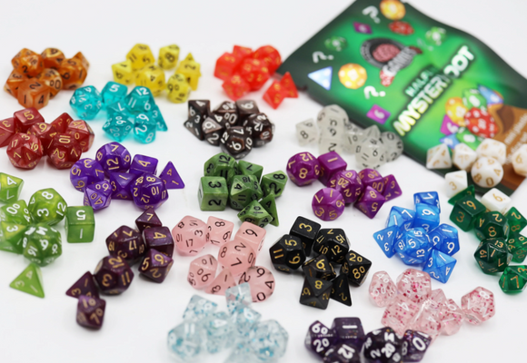 A colorful assortment of polyhedral dice from Foam Brain Games' Mystery Loot: Halfling Dice. The image features various shapes and colors, including translucent, opaque, and speckled options, each marked with numbers. The packaging is partially visible, showcasing the game's fun and whimsical theme.