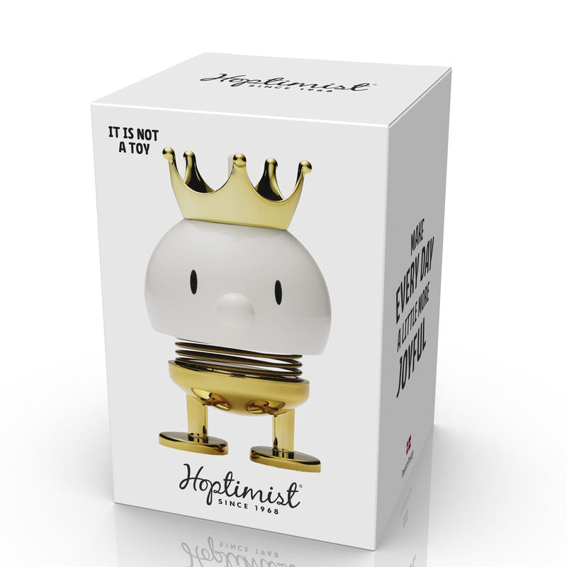 Hoptimist Prince White, a whimsical figurine with a charming design featuring a spring body, a golden crown, and an uplifting expression. The packaging states 'It is not a toy,' and promotes a joyful daily experience.