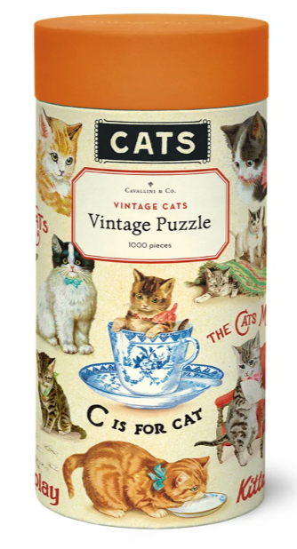Vintage-style cylindrical puzzle tin for 'Cats' by Cavallini & Co., featuring an orange lid and a cream-colored label decorated with multiple cat illustrations and text including 'Cats Vintage Cats Vintage Puzzle' and '1000 pieces'.
