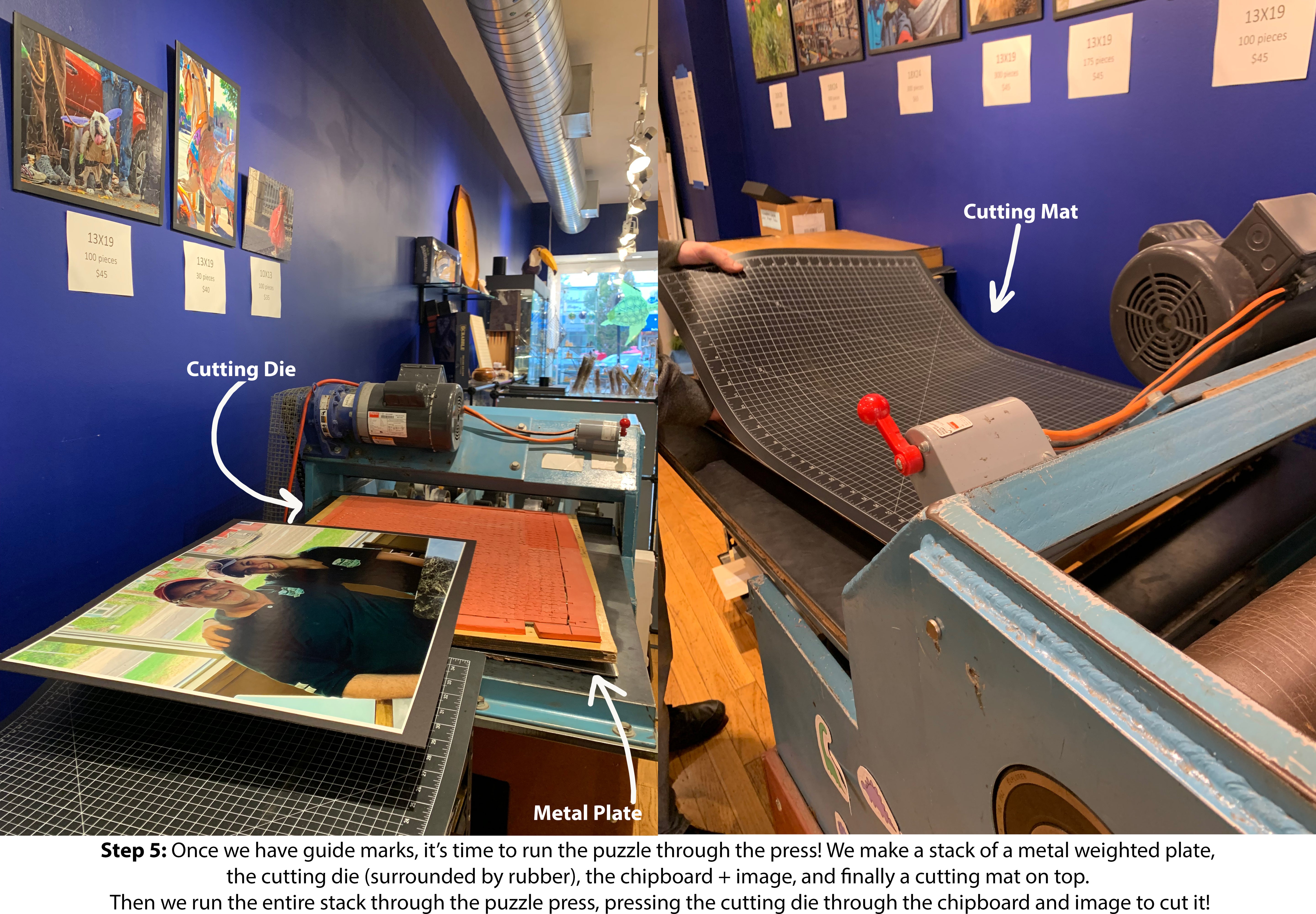 Inside a workshop where custom jigsaw puzzles are made. A cutting die is seen aligned with a colorful photo, ready to be pressed through the machine on a cutting mat. The workspace features a blue wall with various jigsaw puzzle images displayed nearby.