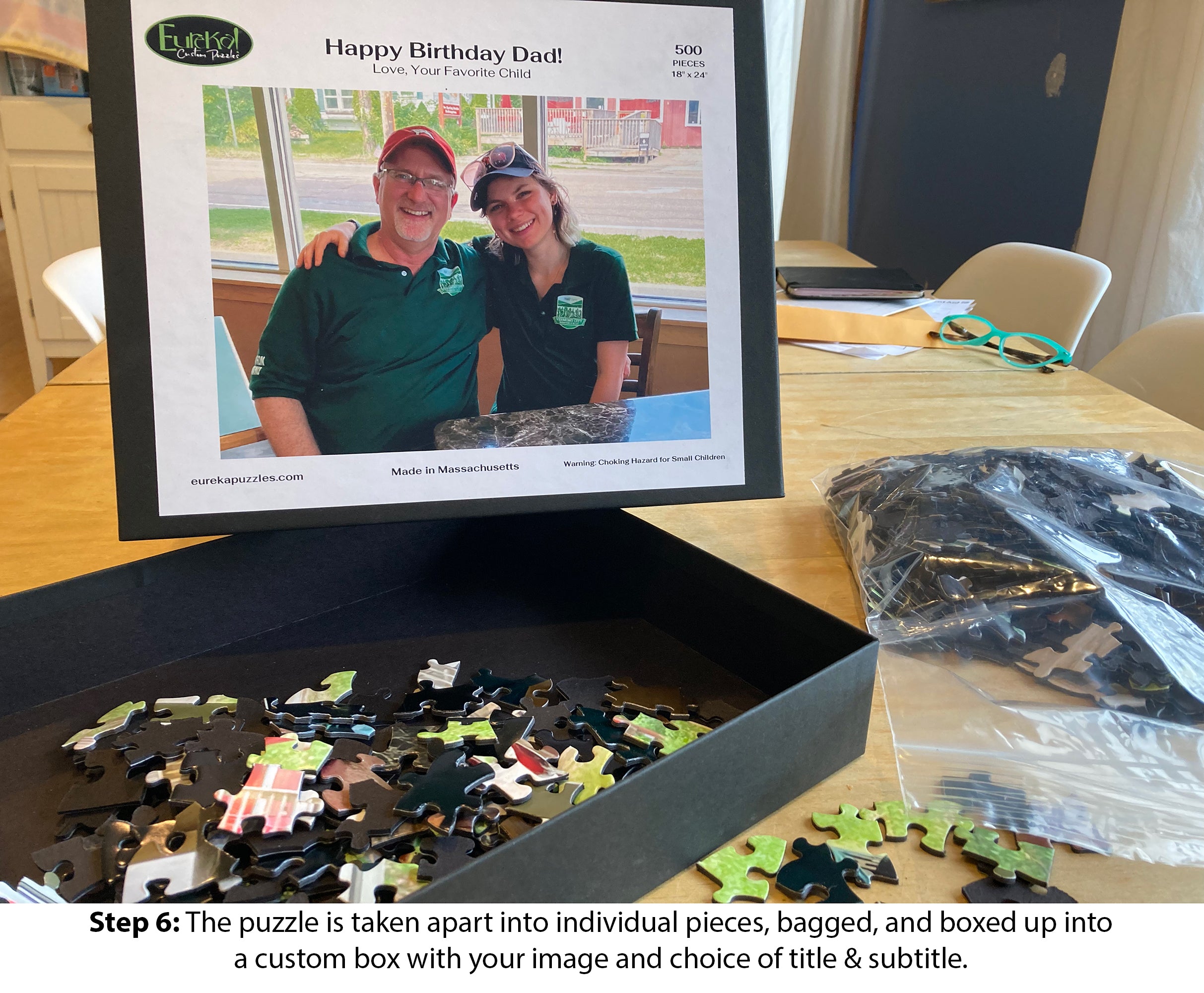 Custom jigsaw puzzle created by Eureka Puzzles, featuring a personalized image and message. The puzzle contains 500 pieces and is displayed with a black box containing scattered pieces. The packaging emphasizes the craft and customization process, ideal for unique gifts.