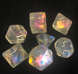 A stunning Ice Fae RPG Dice Set made by Foam Brain Dice, featuring translucent icy-colored dice with intricate numbering. The set includes seven polyhedral dice, reflecting a rainbow of hues under light, designed specifically for tabletop role-playing games.