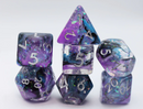 Eventide RPG Dice Set by Foam Brain featuring a variety of colorful, multi-faceted dice in shades of purple and blue with sparkling accents. The set includes a d4, d6, d8, d10, d12, and d20, all displaying clear, white numbers for easy reading, making it perfect for tabletop gaming.