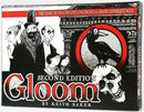 The Gloom board game by Atlas Games, featuring the title prominently on the front of the box. The design includes a stylized illustration of spooky characters, a crow, and a skull, set against a dark background. The box indicates that it is the second edition of the game, themed around misfortune and grim events.