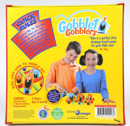 Gobblet Gobblers game box featuring colorful graphics. Includes a wooden game board, 12 wooden gobblers, and illustrated rules. Two children, a boy and a girl, are shown playing the game. The box highlights the gameplay, which is similar to Tic-Tac-Toe, and emphasizes its suitability as a first strategy board game for kids aged 5 and up, including a quote from Dr. Toy.