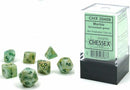 Mini polyhedral dice set in a marble green and dark green color scheme. The seven-die set includes various shapes like d4, d6, d8, d10, d12, d20, and a percentile die. Each die features clear numbers for easy visibility. The set is packaged in a transparent box with a label detailing its contents.