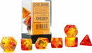 A colorful set of seven polyhedral dice in translucent red, yellow, and gold. The dice are displayed next to their clear container labeled with Chessex branding. Each die features engraved numbers and intricate designs, ideal for tabletop games.