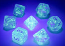 A collection of Borealis Sky blu/wht Lumin Polyhedral dice from Chessex, featuring a translucent design filled with sparkles and glowing numbers. The dice include various shapes like d4, d6, d8, d10, d12, and d20, illuminated under a purple light for a striking visual effect.