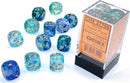 A set of twelve colorful dice in varying shades of blue and transparent materials, embedded with golden dots. The dice are packaged in a clear plastic container with an orange label, showcasing the Nebula Ocean/gld Lumin 12 D6 by Chessex. The container displays the product details and a barcode, highlighting the vibrant colors and glittering elements of the dice, perfect for gaming.