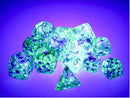 A vibrant collection of Chessex Nebula Ocean/gld Lumin 12 D6 dice, shimmering under purple lighting. The dice feature a translucent design with glitter and distinctive numbers. This colorful assortment includes various shapes, perfect for tabletop games and RPGs.